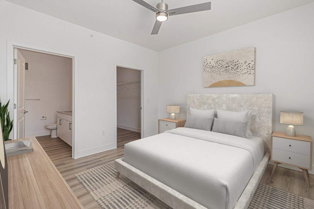 A bedroom with a large bed, a ceiling fan, and a painting on the wall.