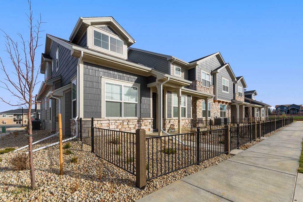 a row of houses with a sidewalk and a fence