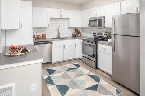 A kitchen with white cabinets and a rug on the floor.