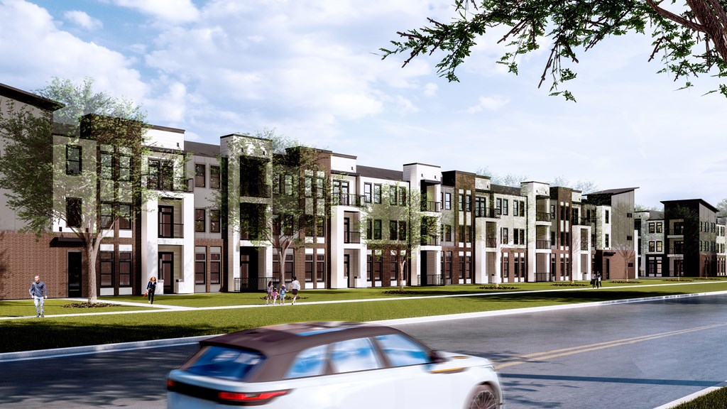 A white car is driving down a street past a building with a lot of windows.