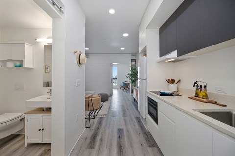 A modern kitchen with white cabinets and a wooden floor.