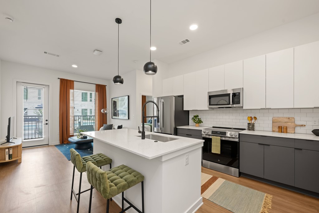 A modern kitchen with a white island and stools.