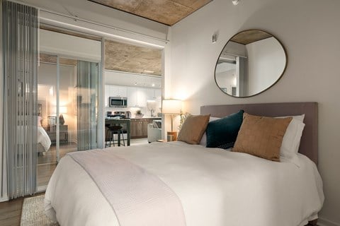 A bedroom with a large bed and a round mirror on the wall.