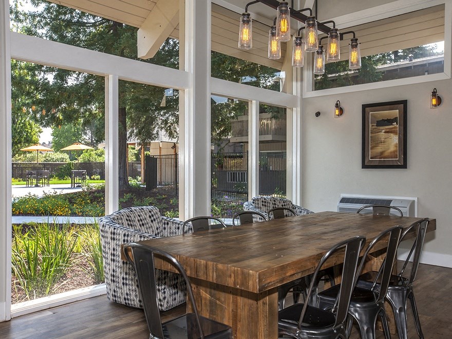 Lounge with wood floors, view of grounds, communal wood table, metal chairs, hip lighting, armchairs