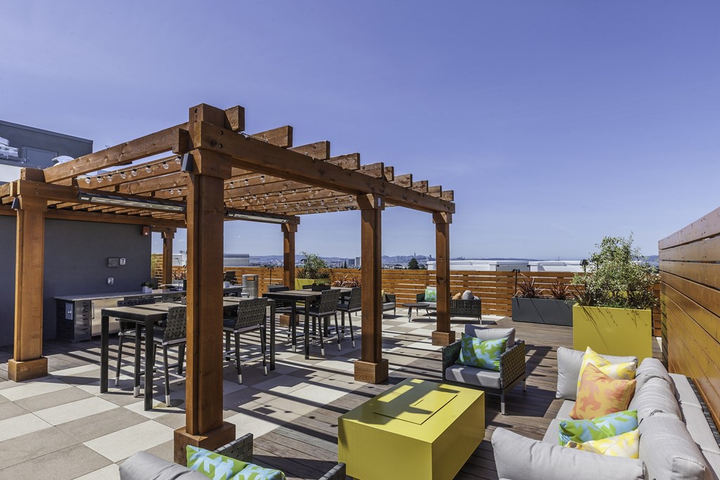 A wooden pergola is over a table and chairs on a patio.
