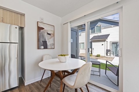 a dining area with a white table and chairs and a refrigerator