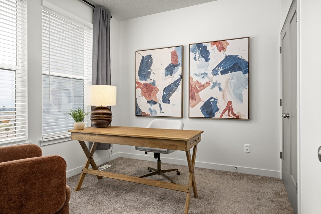 a home office with two paintings on the wall and a wooden desk