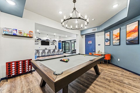 A pool table is in the middle of a room with a blue wall and a chandelier hanging from the ceiling.