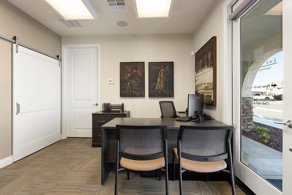 an office with a desk and chairs and a window