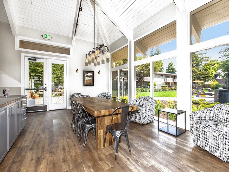 Lounge with view of grounds, communal wood table, metal chairs, cooking counter, hip lighting, armchairs