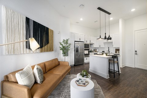 A modern living room with a brown sofa and a kitchen in the background.