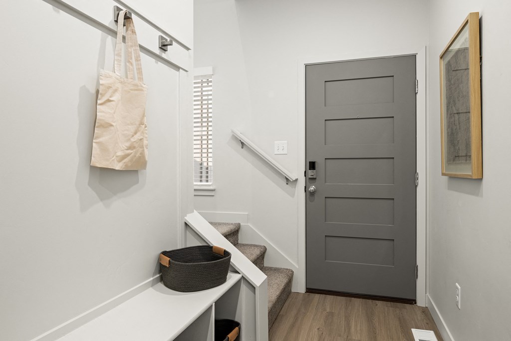 a hallway with a black door and a staircase with a bag hanging on the wall