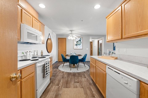 a kitchen with white appliances and a dining room with blue chairs