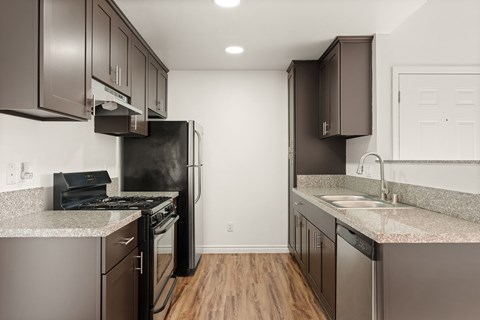 A kitchen with brown cabinets and a black fridge.