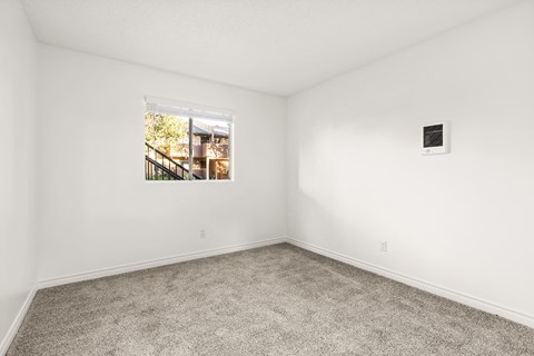 A room with a window showing a view of a building outside.