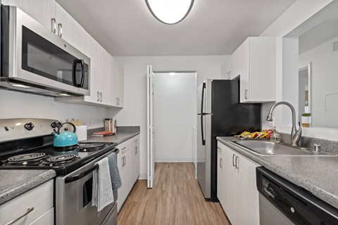 A kitchen with a black refrigerator and white cabinets.