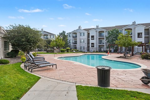 A swimming pool surrounded by a grassy area and apartment buildings.