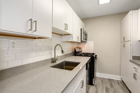 A kitchen with white cabinets and a black dishwasher.