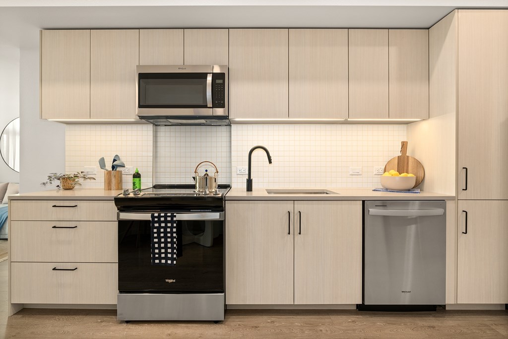 A modern kitchen with a black dishwasher and white cabinets.