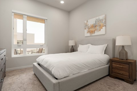 A bedroom with a large bed, a nightstand with a lamp, and a painting on the wall.