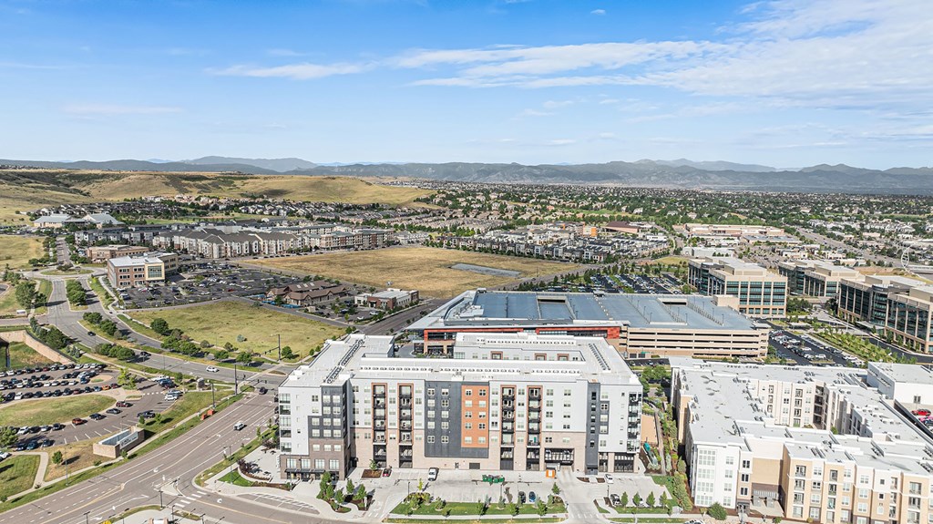 A large building with a red roof is in the center of a parking lot.