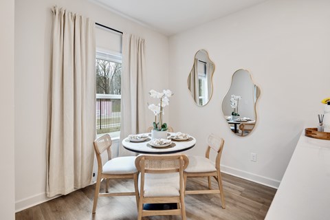 A dining room with a table set for two and a vase of white flowers at Villages at Forest Creek new townhomes for rent in Collierville, TN.