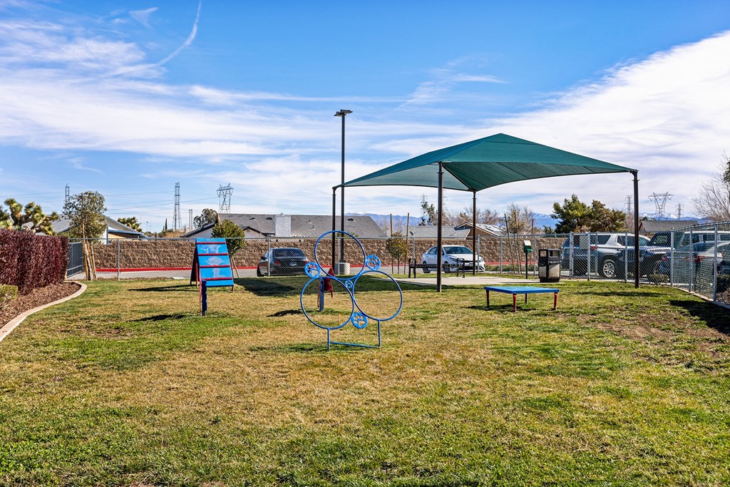 a playground with a green canopy and a blue bench