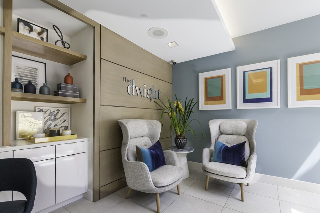 Two chairs are placed in front of a wall with three pictures hanging on it.