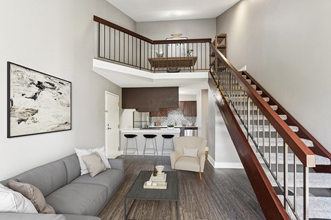 A living room with a grey couch and a painting on the wall.