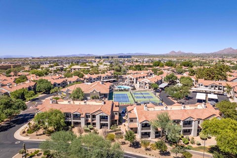 A large building with a tennis court in the middle of a residential area.