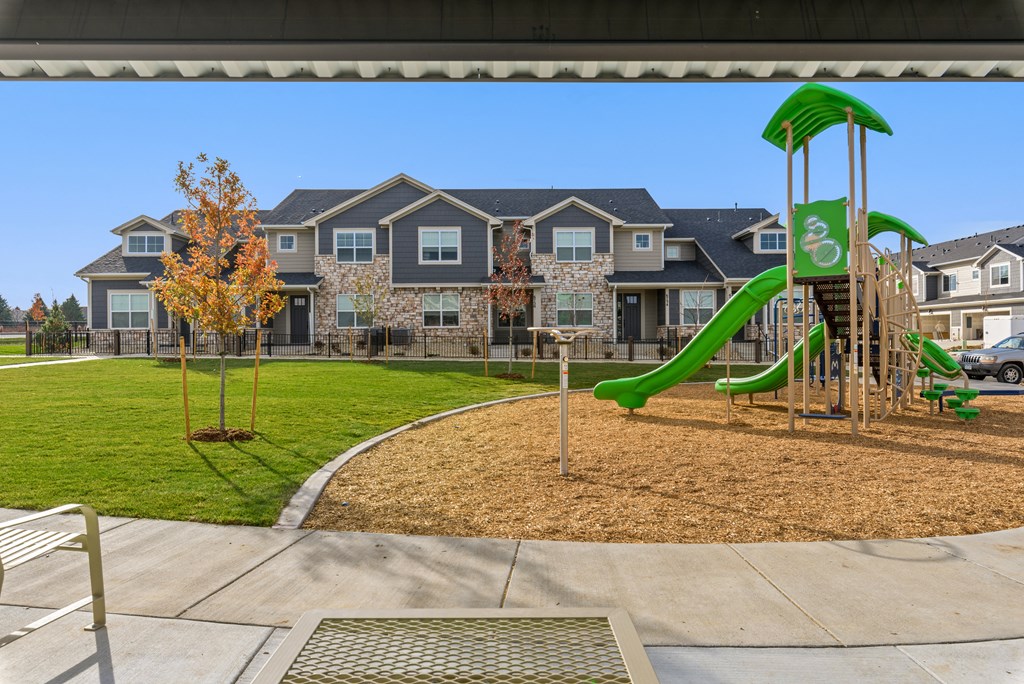 a playground with a green slide in front of an apartment building