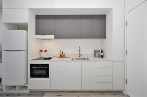 a kitchen with white cabinets and a sink and a refrigerator