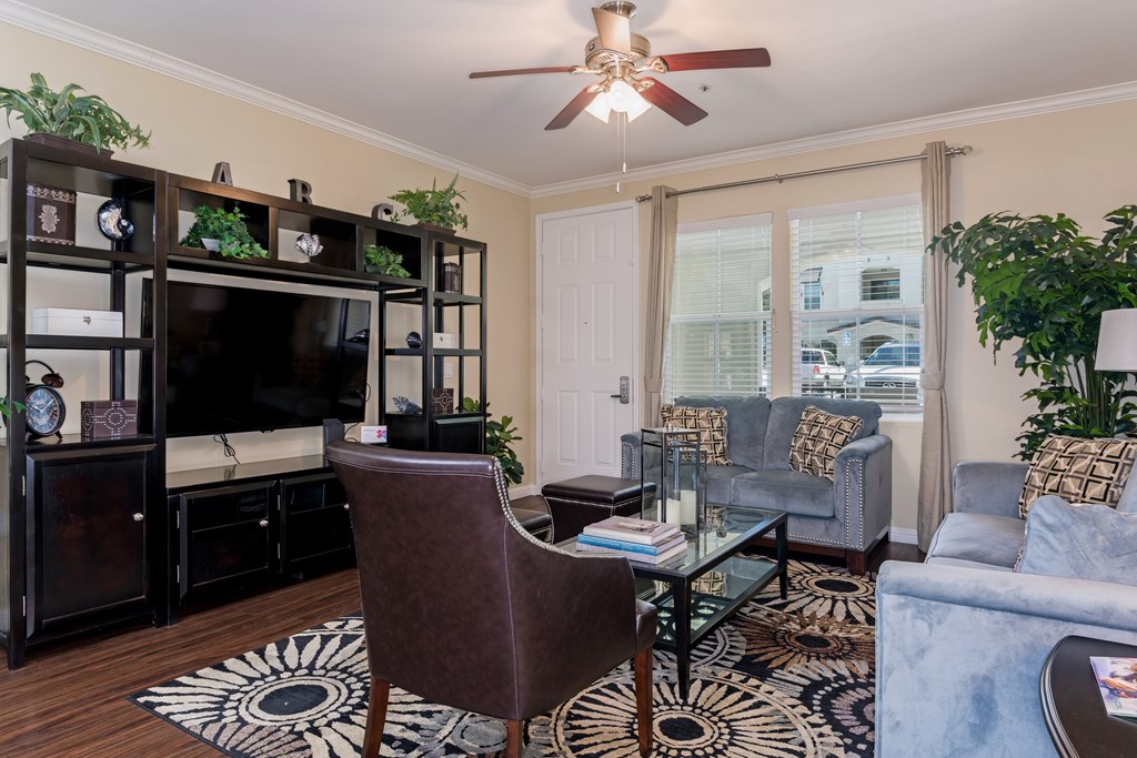 A living room with a brown chair, a glass table, and a ceiling fan.