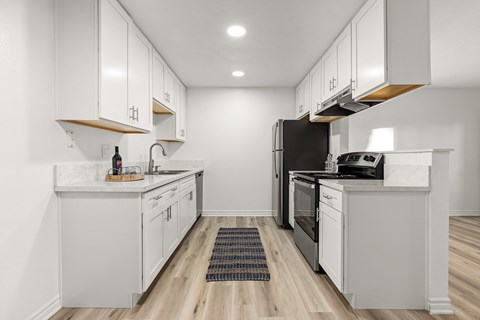 A modern kitchen with white cabinets and stainless steel appliances.