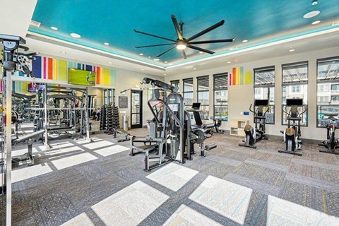 A gym with a variety of equipment and a ceiling fan.