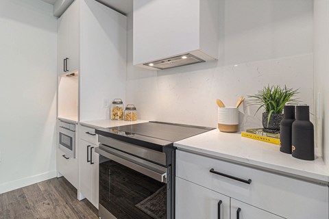A modern kitchen with white cabinets and a stainless steel oven.