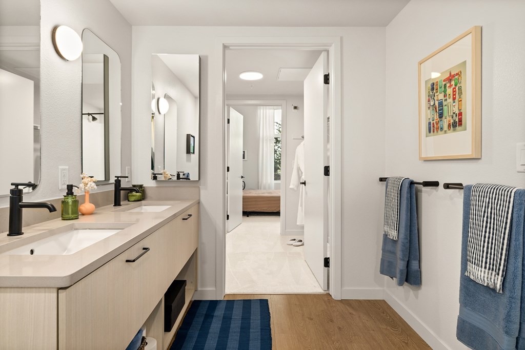 A bathroom with a double sink vanity and a mirror above it.