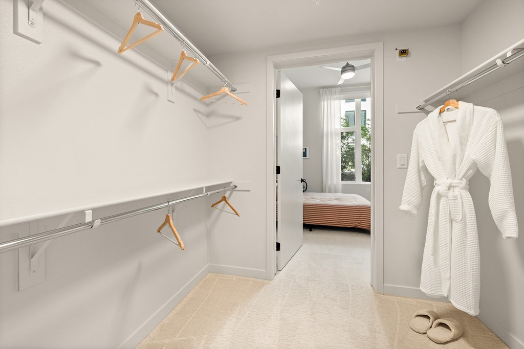 A white robe is hanging on a rack in a white room.