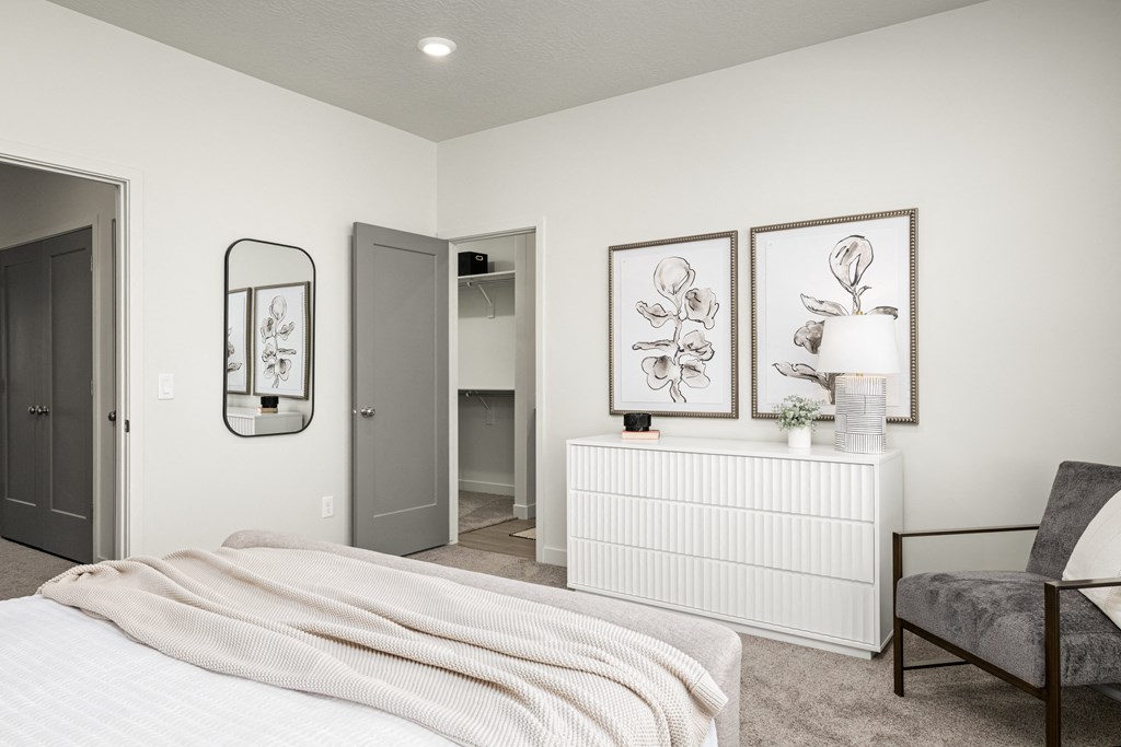 a white bedroom with a bed and a dresser and a mirror