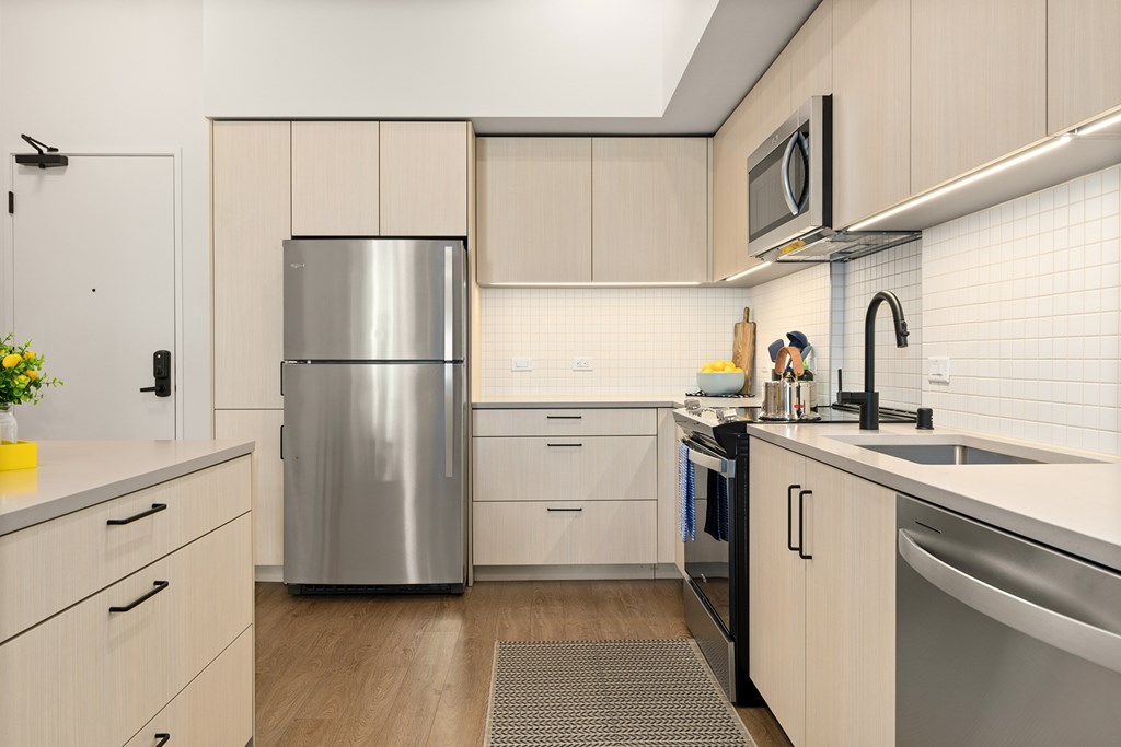 A modern kitchen with a stainless steel refrigerator and a sink.