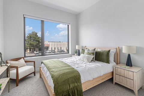 A bedroom with a large bed and a chair by the window.