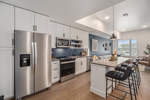 a kitchen with stainless steel appliances and a counter with chairs