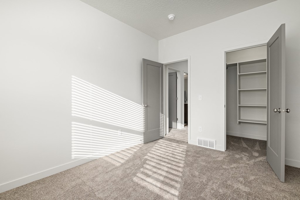 a bedroom with a closet and a window with shadows on the wall
