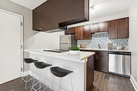 A kitchen with a white counter and black stools.