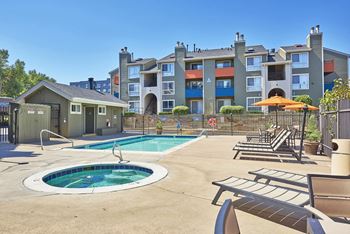 A pool with a hot tub in front of apartment buildings.