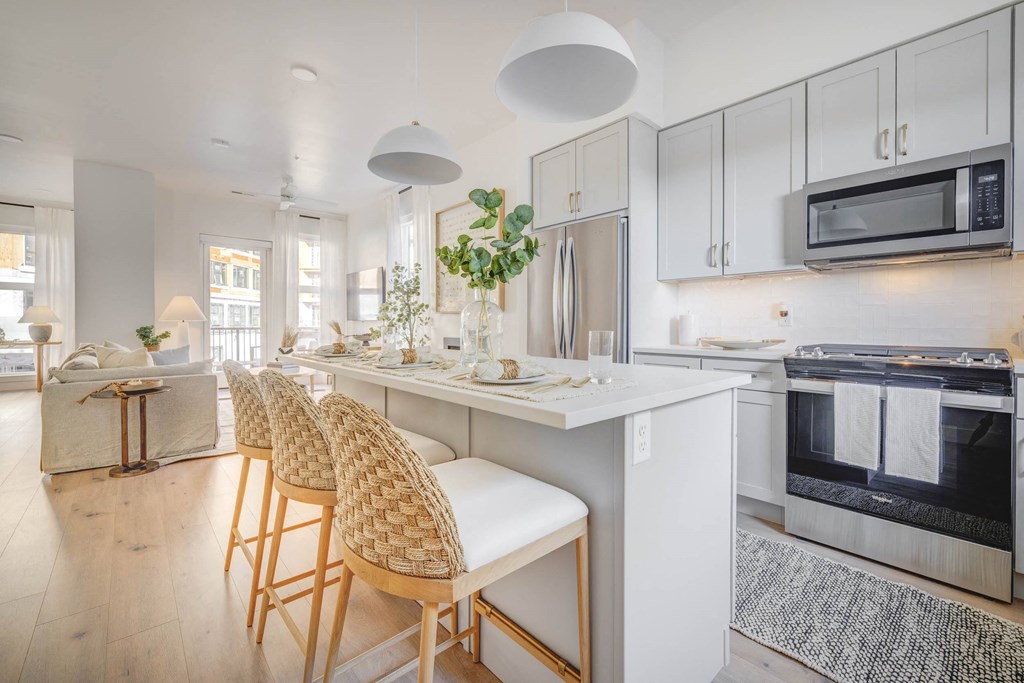 a kitchen with white cabinets and a long island with three chairs