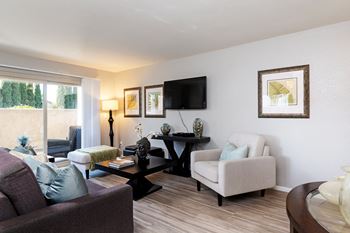 a living room with a couch and chairs and a tv at The Casas Apartments, San Diego, 92126