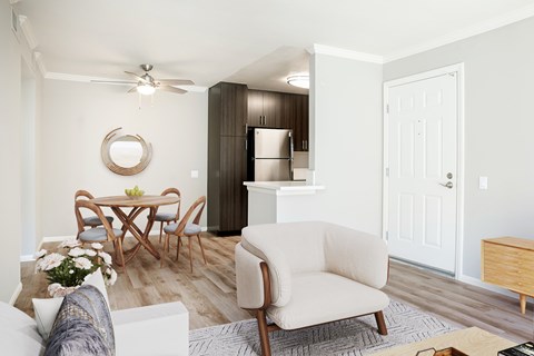 A living room with a white couch, a wooden dining table, and a white chair.
