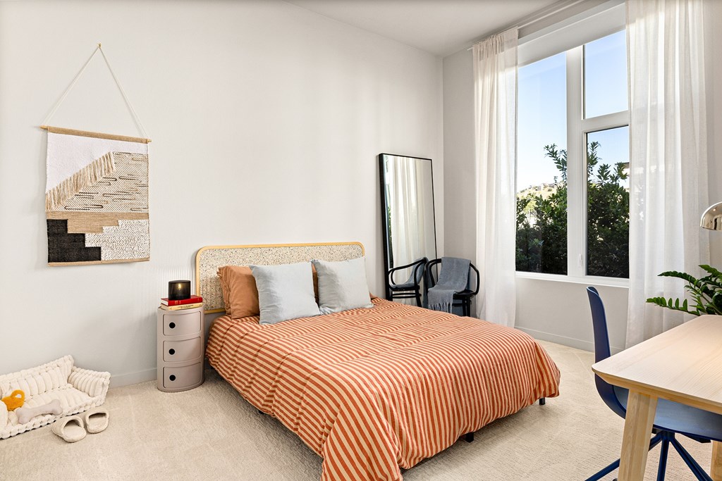 A bedroom with a bed, chair, and a painting on the wall.