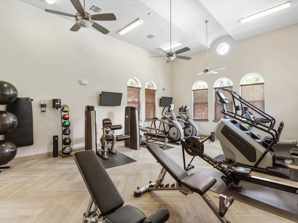 a gym with weights and other exercise equipment in a room with windows